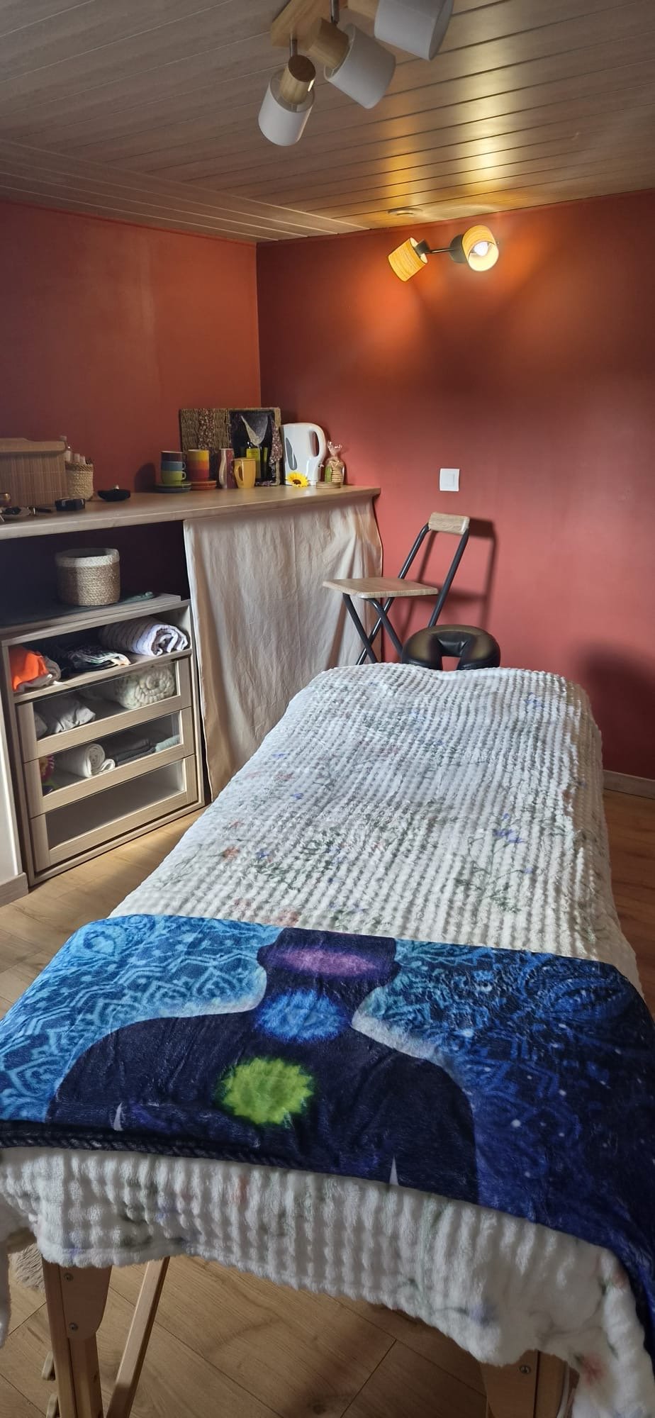 Le cabinet de massages holistiques de Claire Frugier, avec sa table de massage, ses murs terracotta et son mobilier en bois
